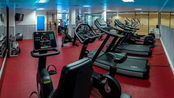 Una palestra con tapis roulant, macchinari per pesi e palle da ginnastica.