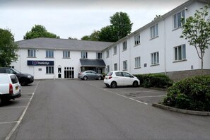 Ein Travelodge Hotel mit Parkplatz und mehreren parkenden Autos davor.