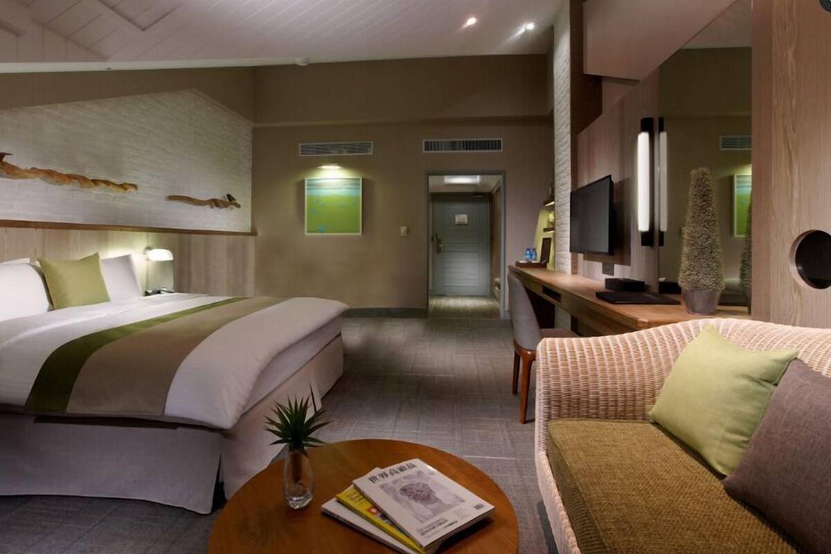 Una habitación de hotel con una cama, un sofá, una mesa de centro, un televisor y un escritorio.