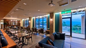 Um hall de hotel moderno com um balcão de recepção comprido, área de estar e grandes janelas com vista para a cidade.