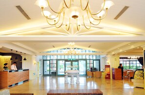 A spacious lobby with a reception desk, a large chandelier, and a view of the outside through large windows. - Yangmingshan Tien Lai Resort & Spa (New Taipei City)