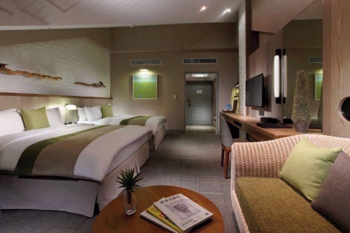 Habitación de hotel con dos camas, un sofá, un escritorio y un televisor.