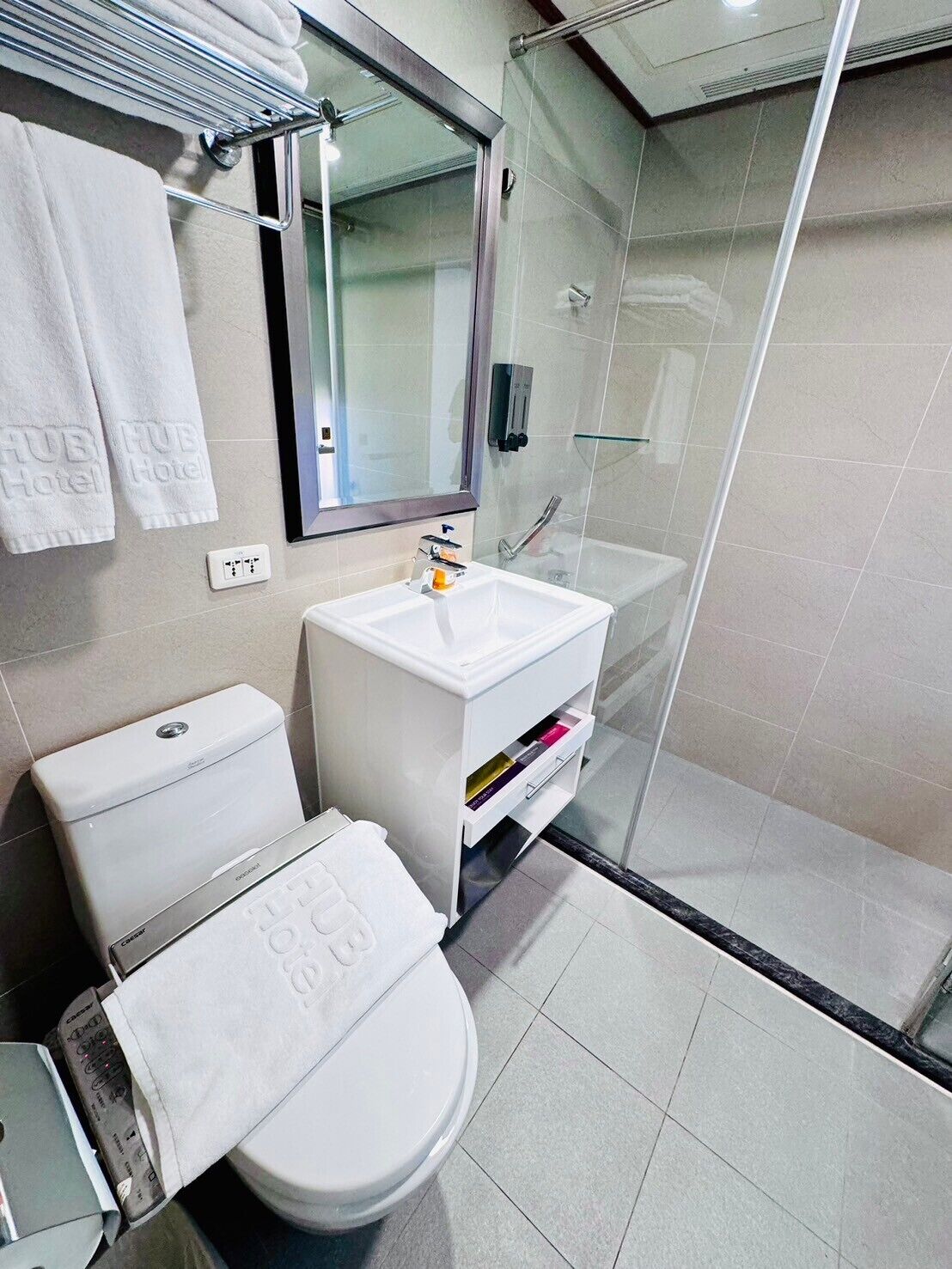 A modern bathroom with a toilet, sink, and glass shower enclosure.