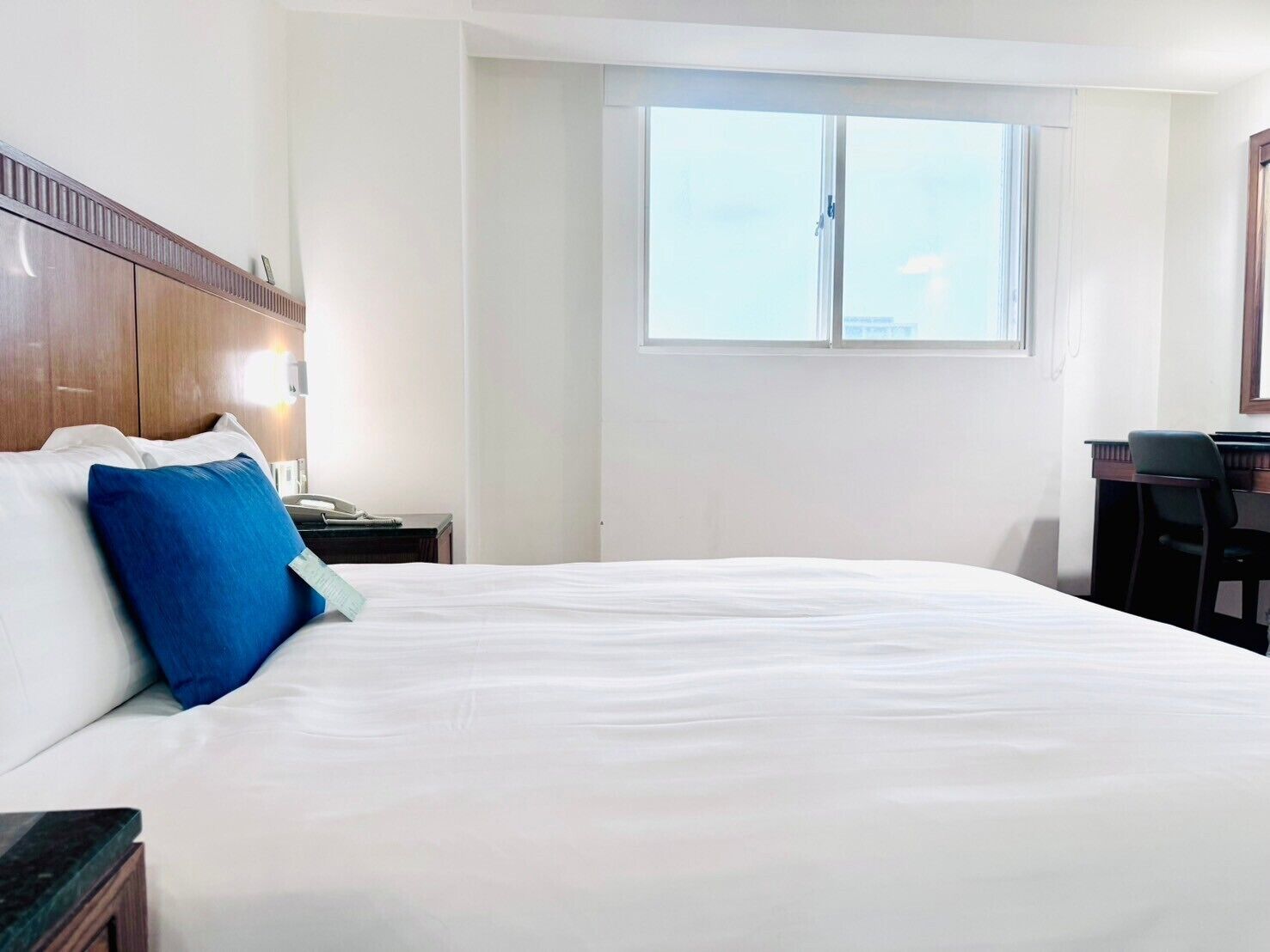 A hotel room with a large bed, a desk, and a window.