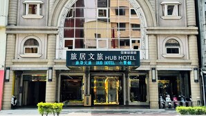 Un hotel con una amplia entrada en arco, múltiples ventanas y un cartel con el nombre del hotel y sus servicios.