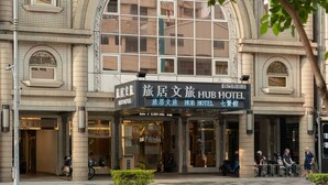 Un hotel con fachada de azulejos, amplias ventanas y un letrero que dice 'Traveling Hub Hotel'.