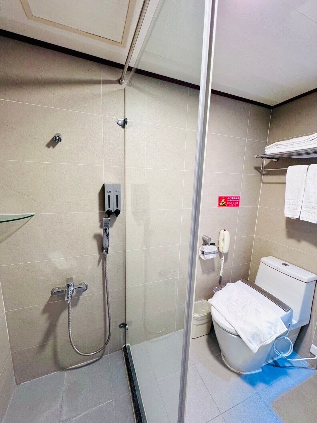 A bathroom with a glass-enclosed shower, a toilet, and a towel rack.