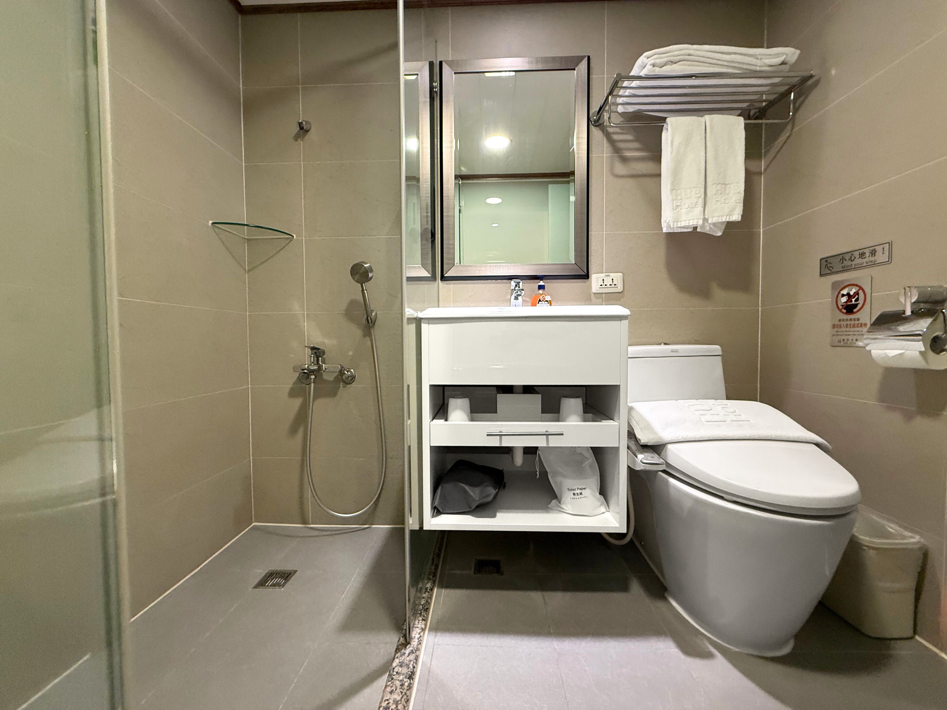 A modern bathroom with a shower, toilet, sink, and towel rack.