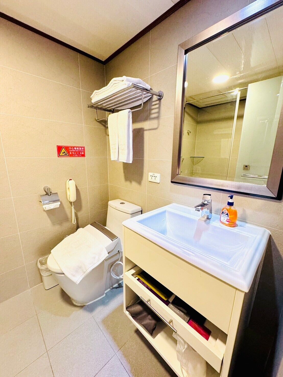 A bathroom with a toilet, sink, mirror, and towel rack.