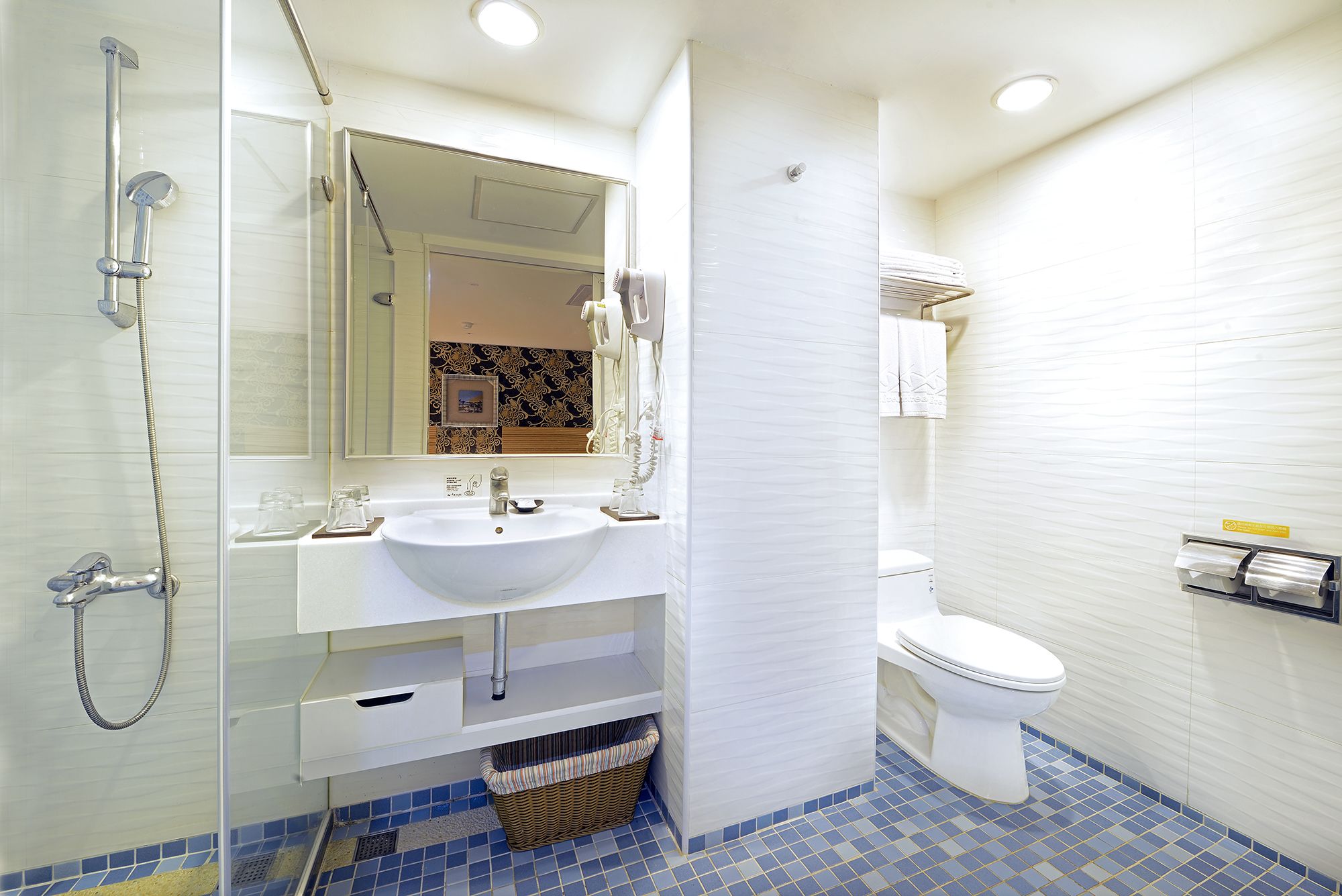 Un baño con lavamanos, espejo y retrete blanco.