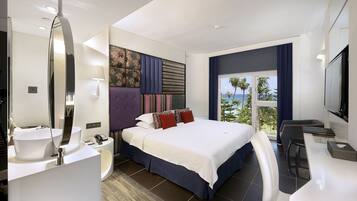 Une chambre d’hôtel moderne dotée d’un grand lit, d’une salle de bain avec un miroir et un lavabo, et offrant une vue sur l’océan.