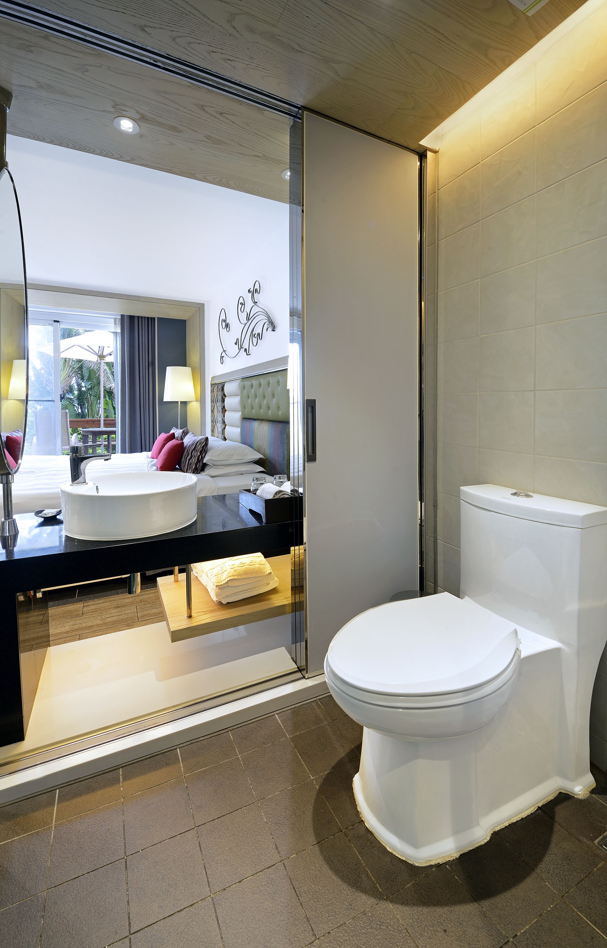 A modern bathroom with a large mirror, a round sink, and a toilet.