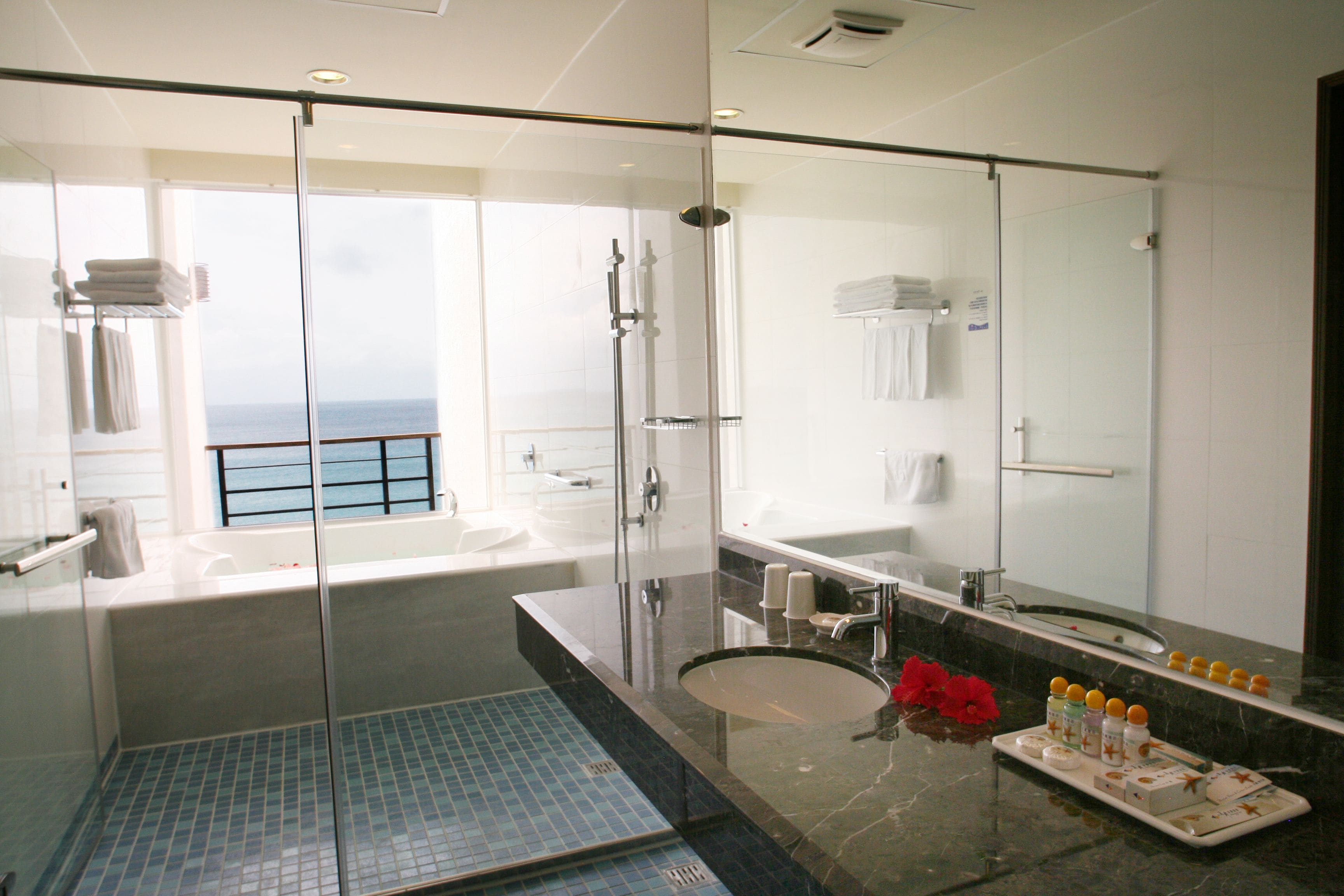 A modern bathroom with a glass-enclosed shower, a large bathtub, and a vanity with a mirror.