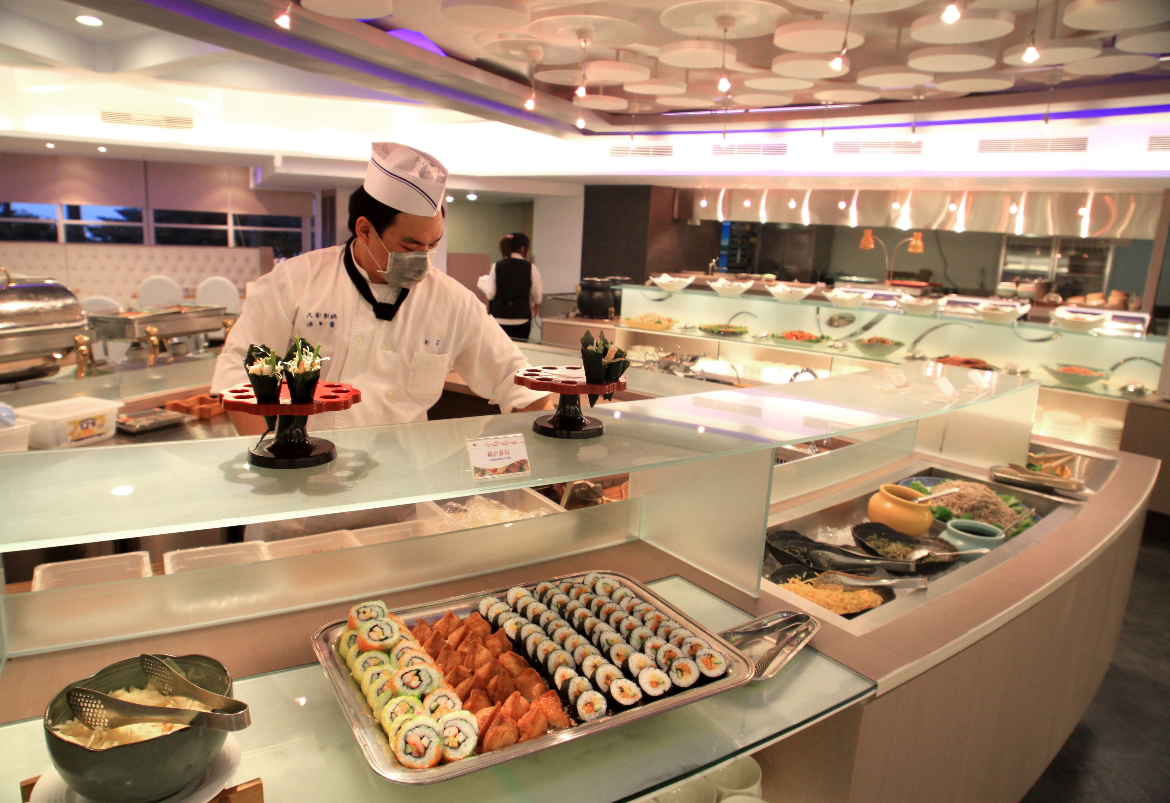 Un espace buffet proposant une variété de plats et un chef qui prépare les aliments.