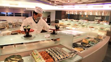 A buffet area with various food items and a chef preparing food.