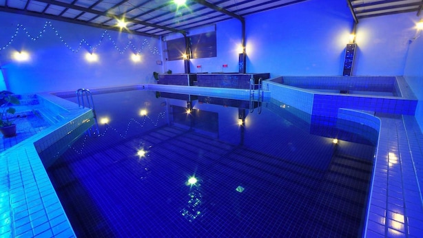 Una piscina interior amb il·luminació blava, parets de rajola i una escala que hi baixa.