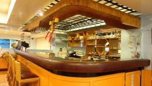 Zona de bar amb un mostrador corbat, prestatgeries de fusta i decoracions penjants.
