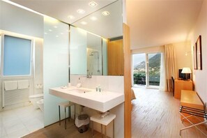 Enjoy a serene retreat with a spacious bathroom, seating area, and outdoor views.