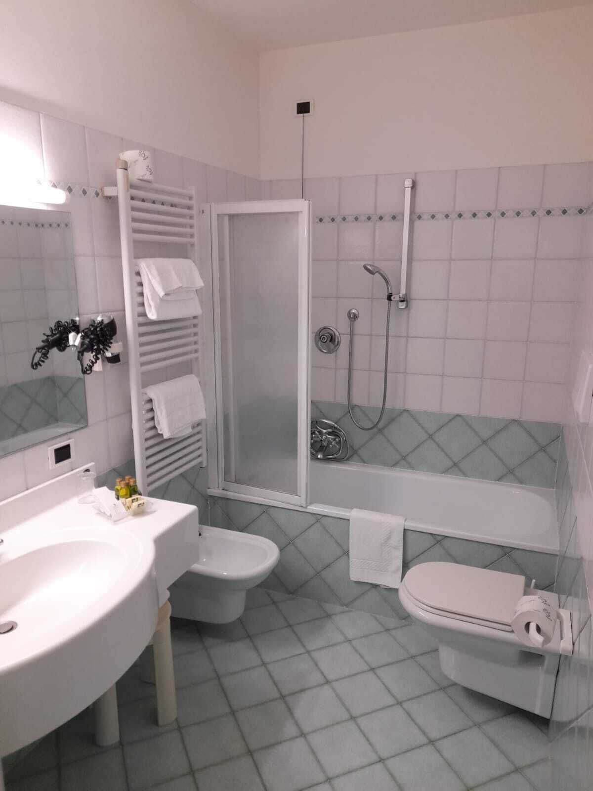 Un baño moderno con lavamanos, inodoro y zona de ducha blancos.