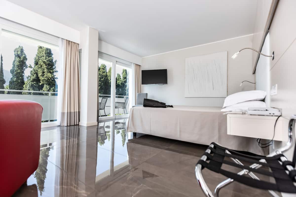 Une chambre d’hôtel moderne dotée d’une grande fenêtre, d’un lit, d’un bureau avec un ordinateur et d’une chaise.