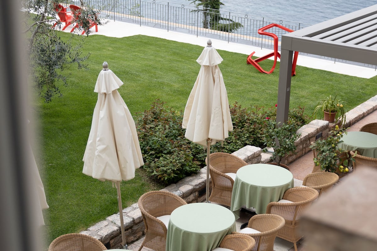 Une terrasse dotée de tables et de chaises en osier, de parasols et offrant une vue sur un lac.