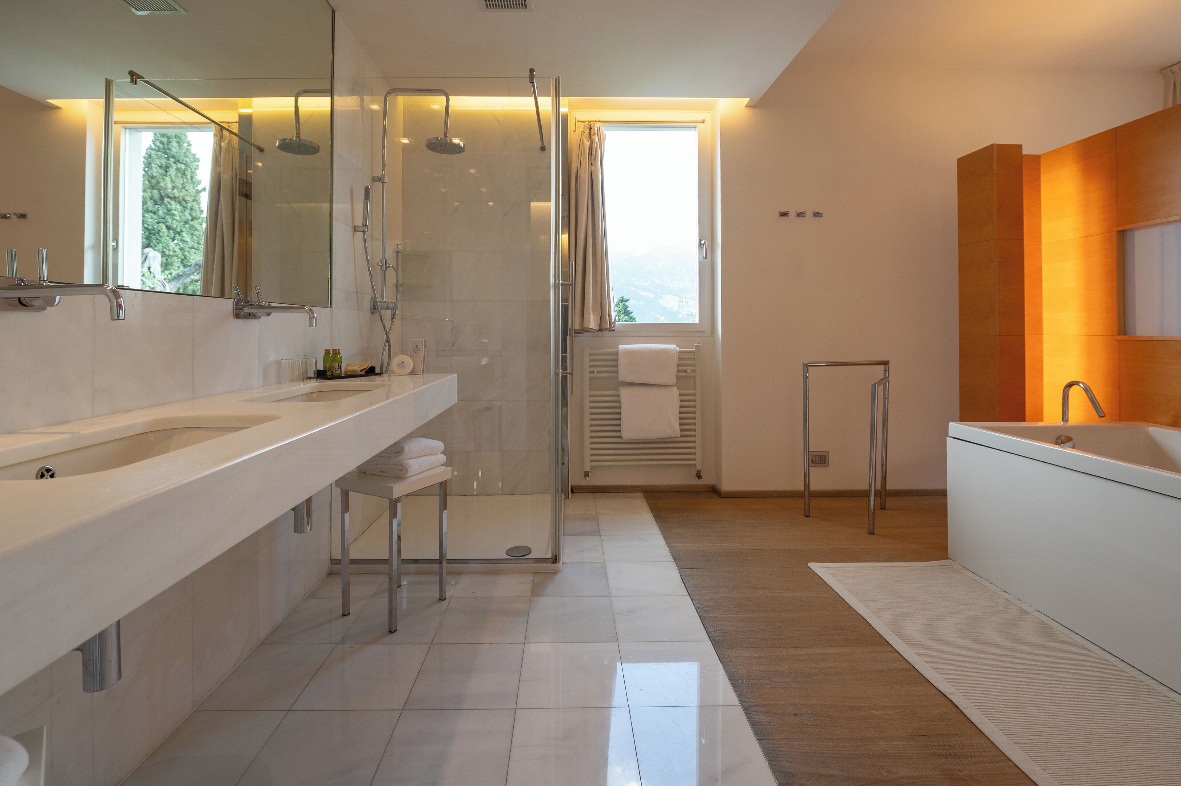 A modern bathroom with a large shower, a bathtub, and a vanity with a mirror.