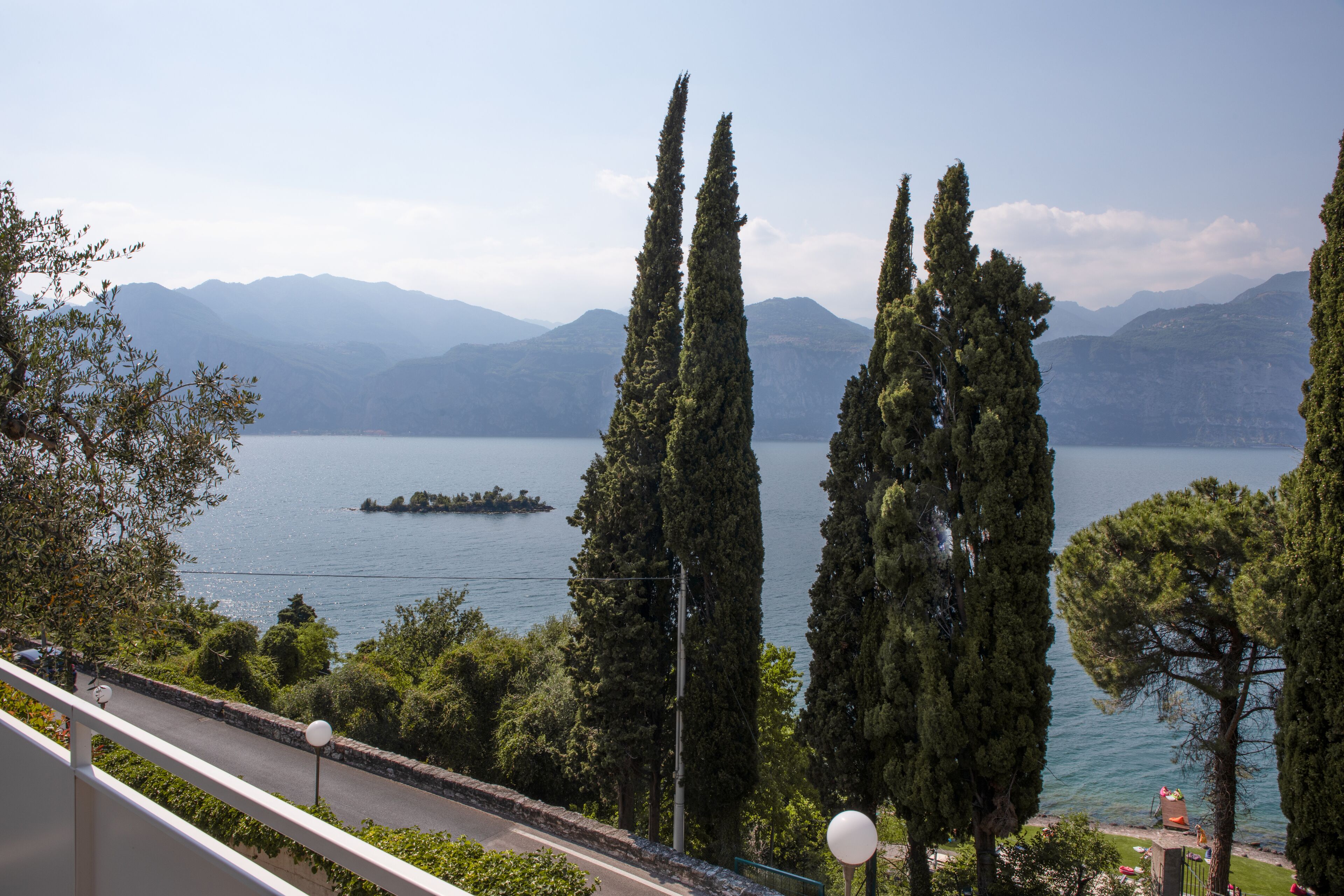 A scenic view of a lake with tall cypress trees and mountains in the background.
