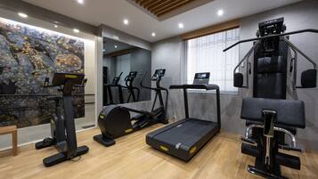 Un gimnasio moderno con cintas de correr, elípticas y una máquina de remo.