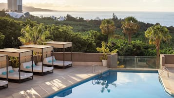 Zona de piscina con sillones de descanso y vista al océano.