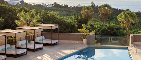 Zona de piscina con sillones de descanso y vista al océano.