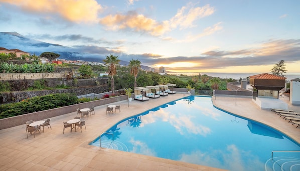 Una piscina al aire libre, sombrillas, sillones reclinables de piscina