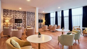 A modern hotel lobby with a patterned wall, comfortable seating, a flat-screen TV, and large windows with curtains. - Aluasoul Orotava Valley (Puerto de la Cruz)