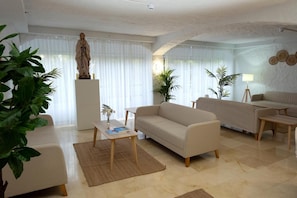 Un salon avec un canapé, une table basse et une statue posée sur un piédestal.