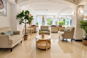 Un salon spacieux avec un plafond haut, plusieurs coins salon et une table basse centrale.