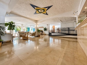 Un hall d’entrée spacieux avec un plafond haut, une étoile décorative au centre et un escalier.