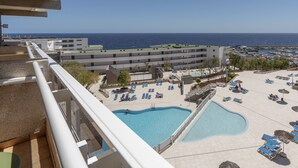 A hotel with a pool area, multiple lounge chairs, and a view of the sea. - Alua Atlantico Golf (San Miguel de Abona)