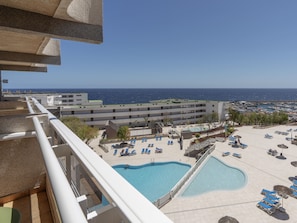 A hotel with a pool area, multiple lounge chairs, and a view of the sea. - Alua Atlantico Golf (San Miguel de Abona)
