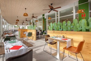 A restaurant with wooden walls, cactus decorations, and tables set for dining.