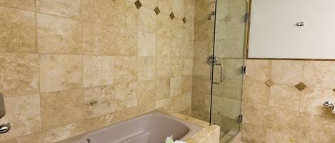 A bathroom with a bathtub, a glass shower enclosure, and a white cabinet.