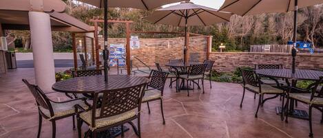 An outdoor patio with stone flooring and metal tables and chairs.