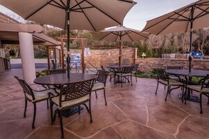 Un patio al aire libre con suelo de piedra y mesas y sillas de metal.