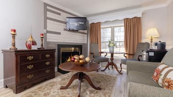 A living room with a fireplace, a television, a sofa, a coffee table, and a wooden cabinet.