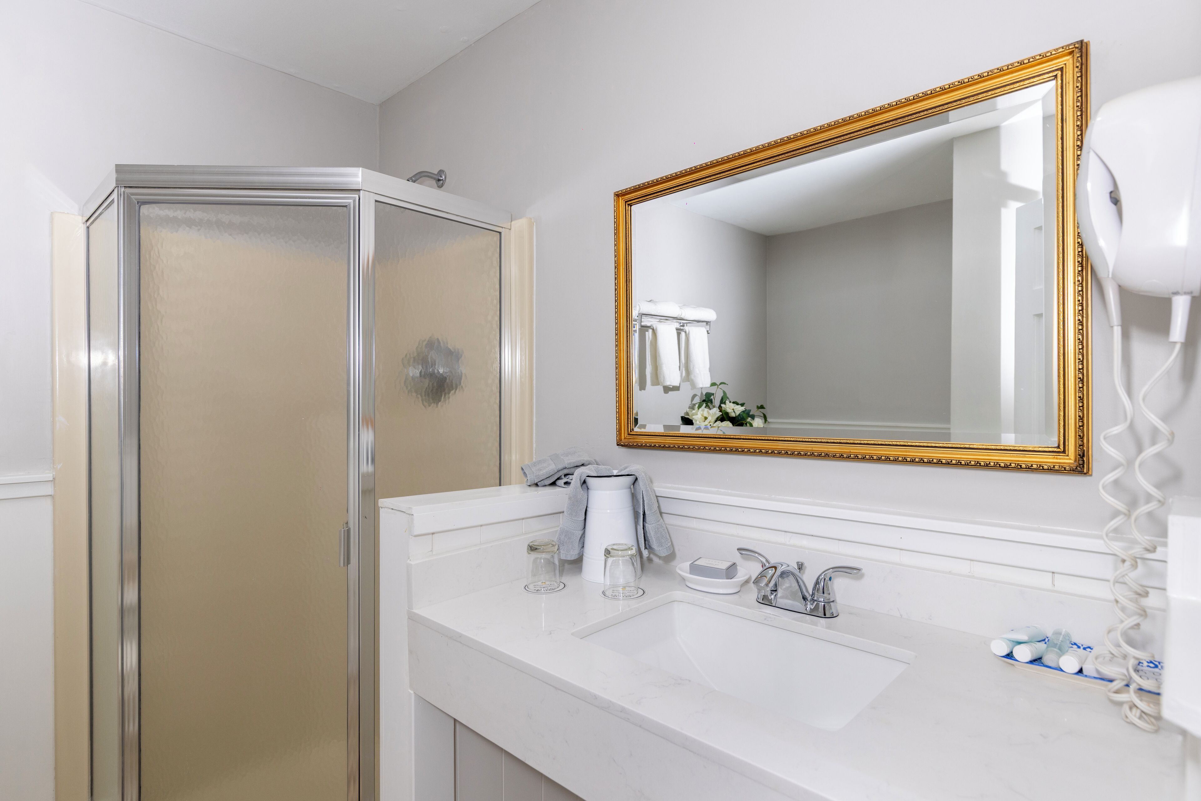 Een badkamer met een douche, wastafel en een grote spiegel.