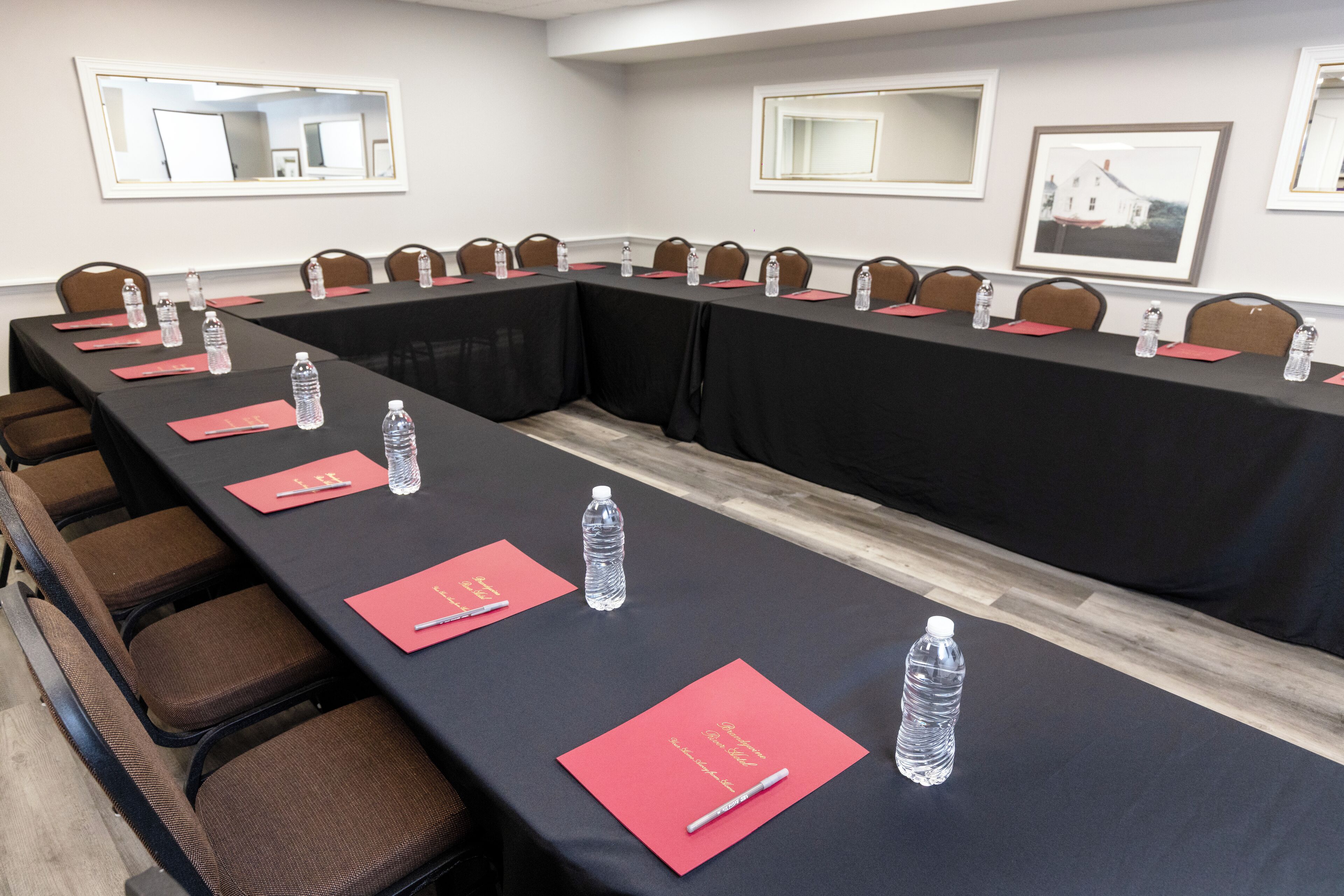 Ein Konferenzraum mit langem Tisch, Stühlen, Wasserflaschen und roten Ordnern.