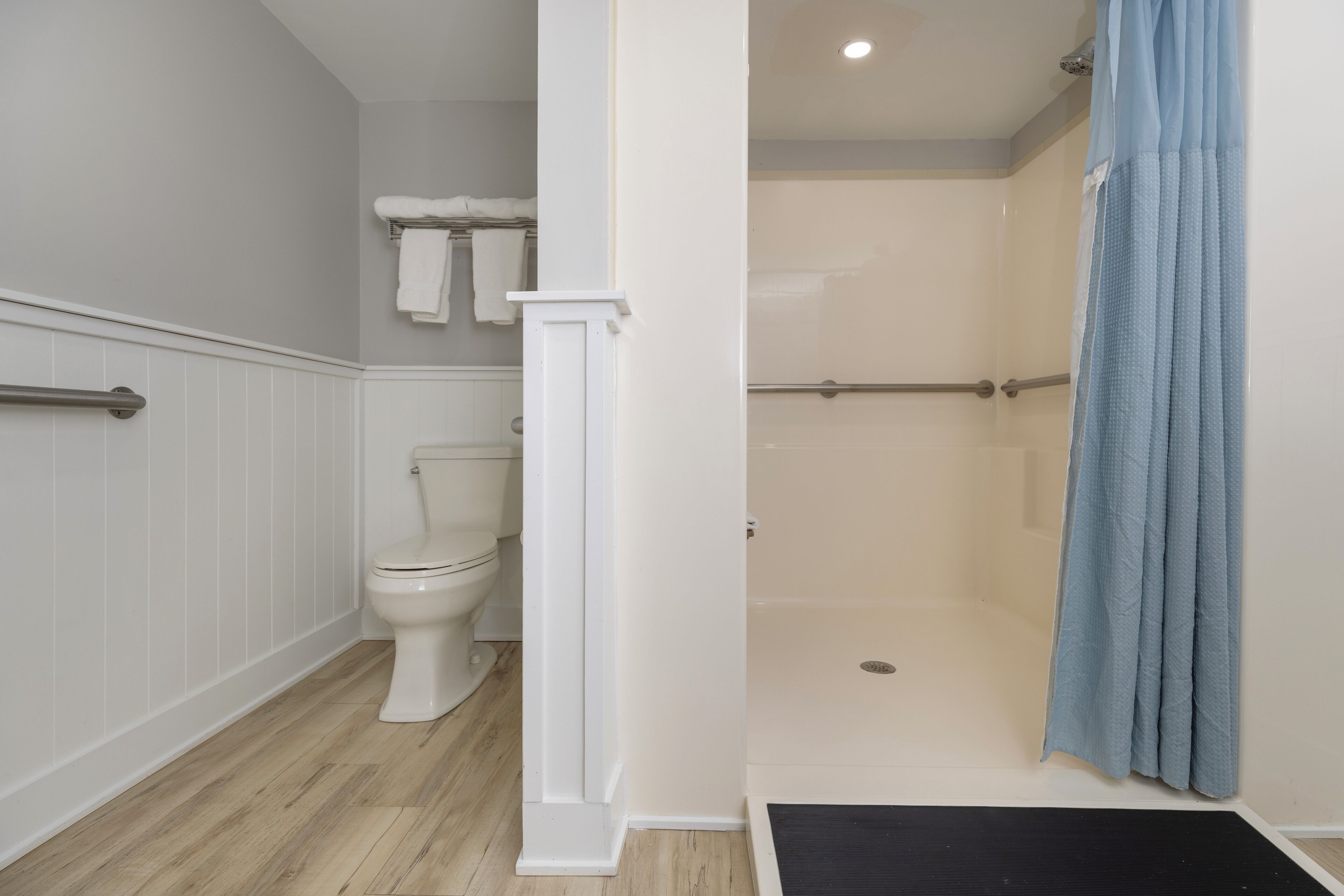 A bathroom with a toilet, shower, and a towel rack.