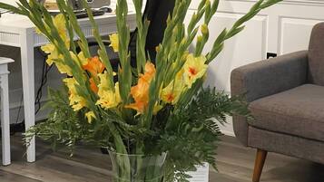 Un escritorio con un jarrón de flores, una computadora portátil y folletos sobre una mesa blanca.