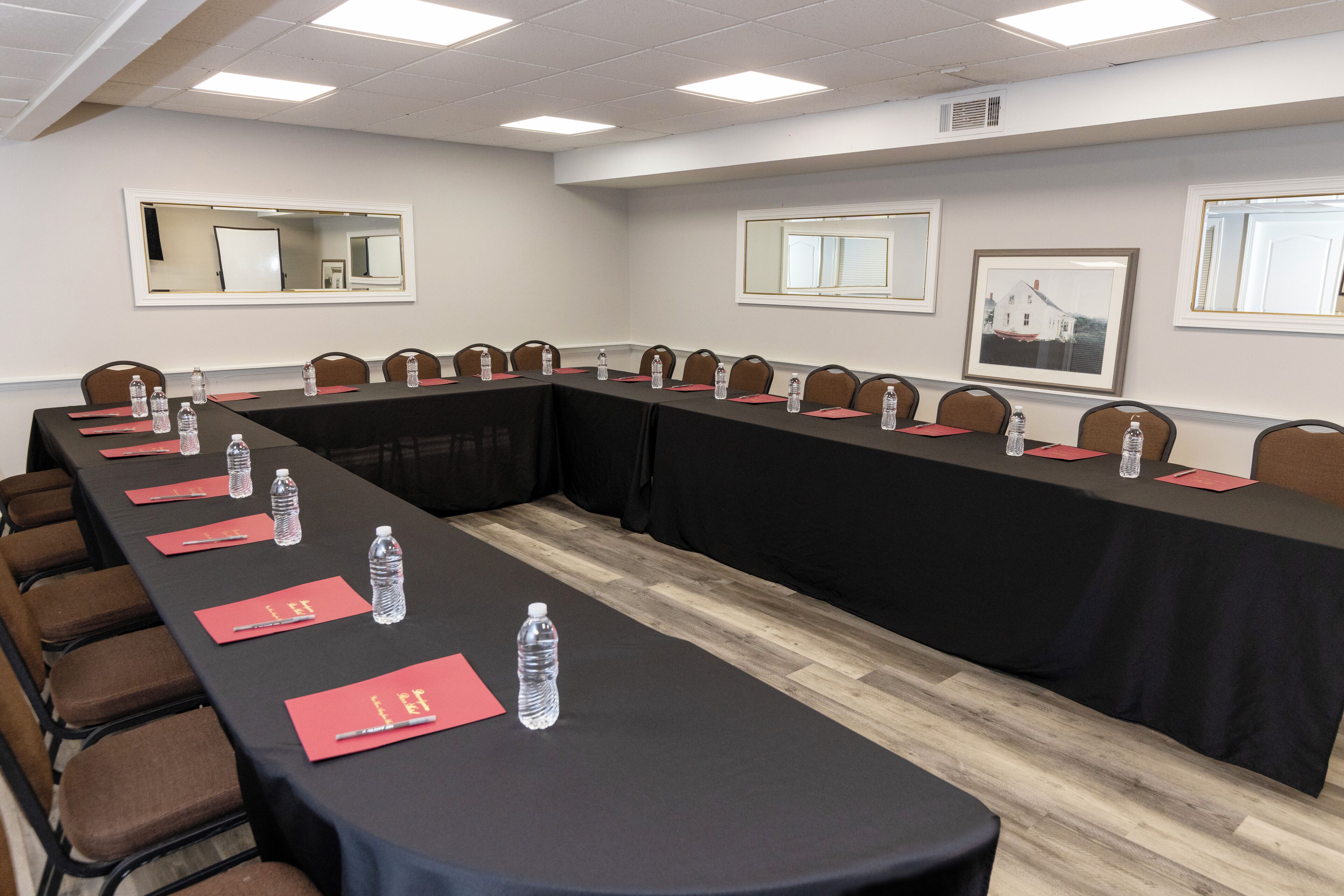 Un salón de conferencias con una larga mesa, sillas, botellas de agua y tarjetas de nombre.