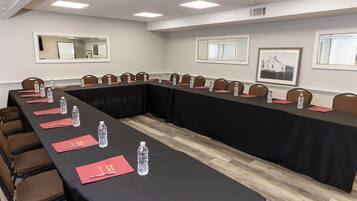 Un salón de conferencias con una larga mesa, sillas, botellas de agua y tarjetas de nombre.
