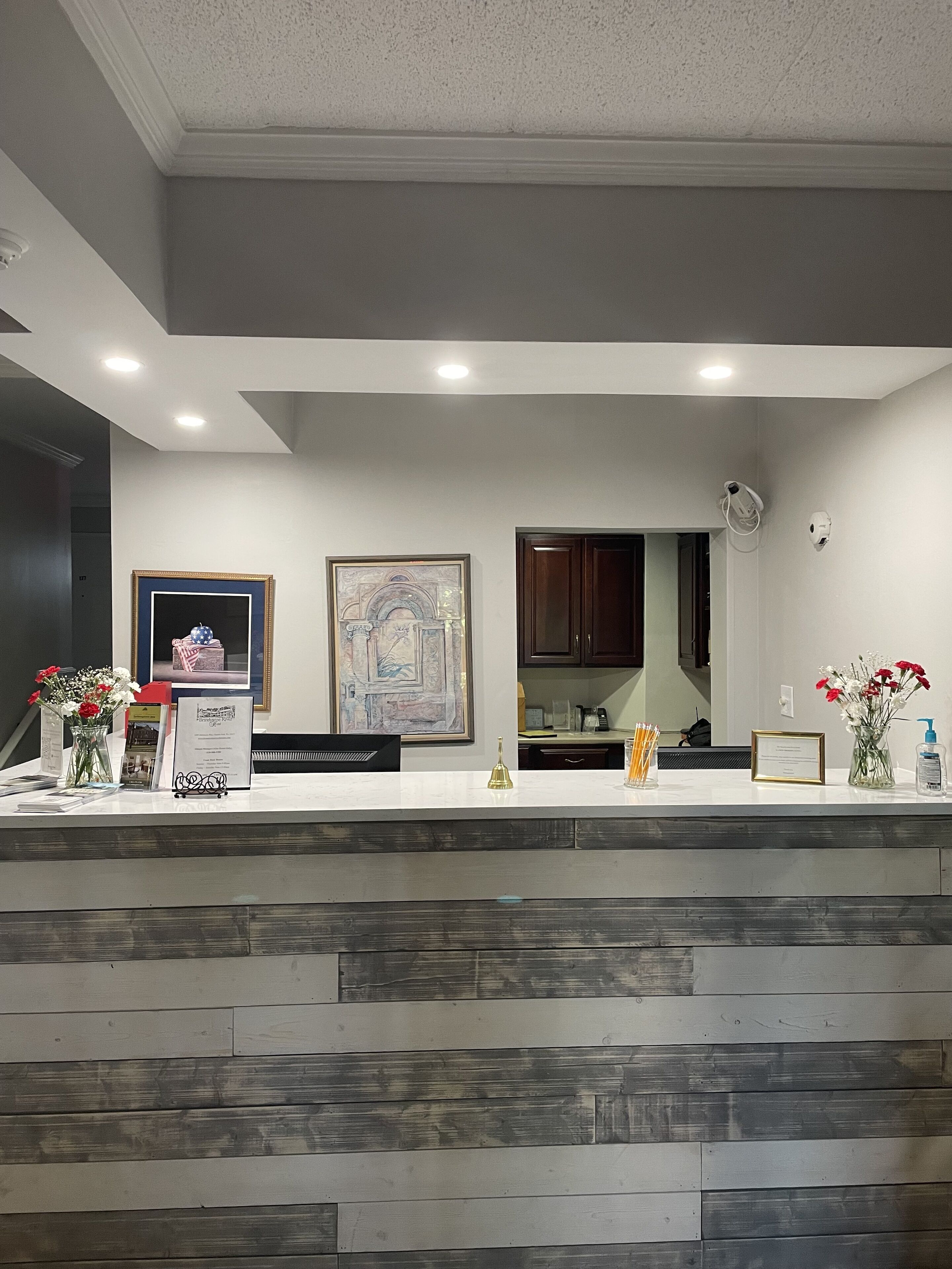 A reception desk with a white countertop, framed artwork, and a wooden panel base.