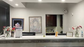 A reception desk with a white countertop, framed artwork, and a wooden panel base.